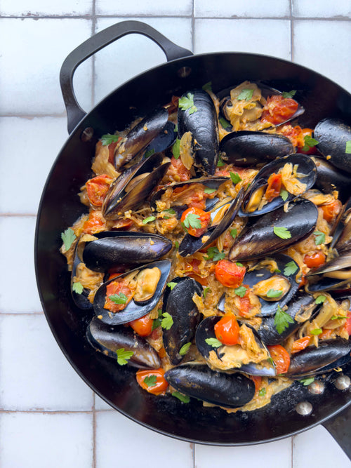 Mussels in a tomato and herb broth, cooked in a cast iron pan