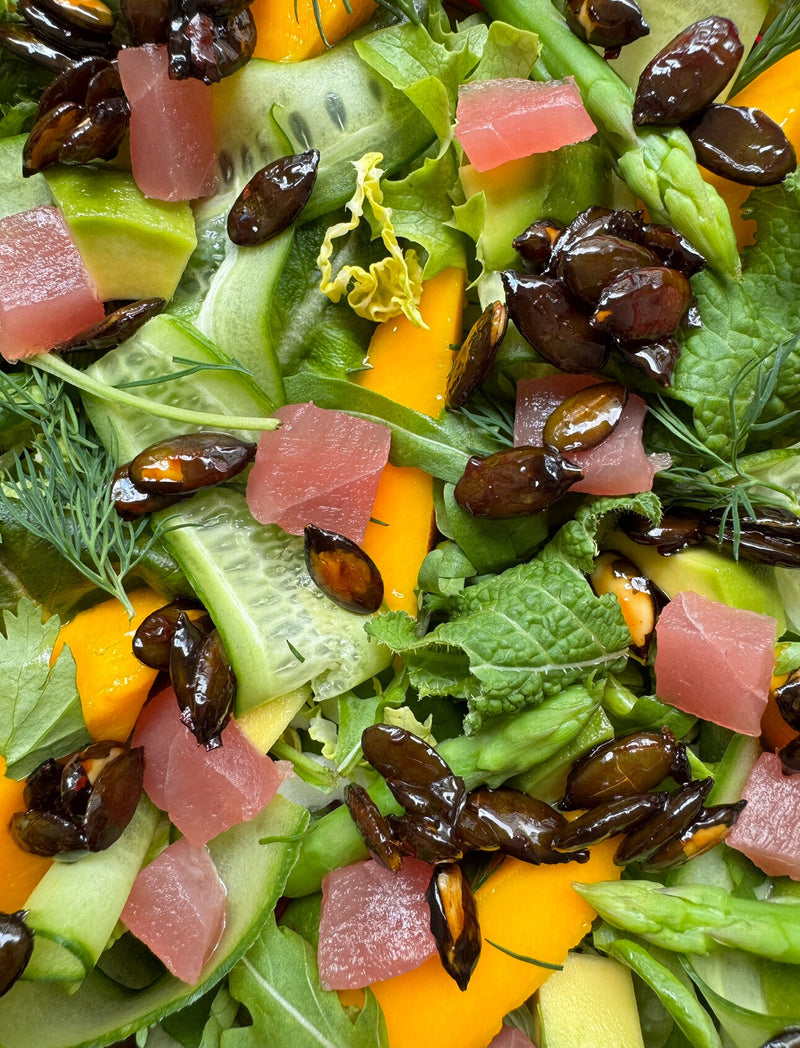 Close-up tuna salad of cucumber ribbons, mango, watermelon, asparagus and olives