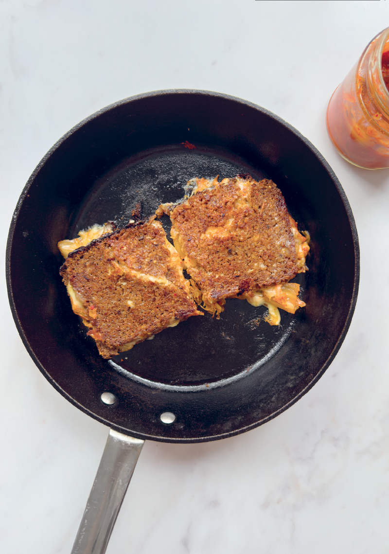 Kimchi toasted sandwich cut in half in a frying pan